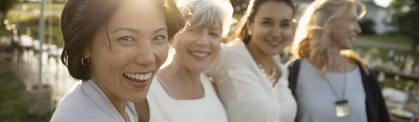 Group of adult female friends smiling and walking through garden